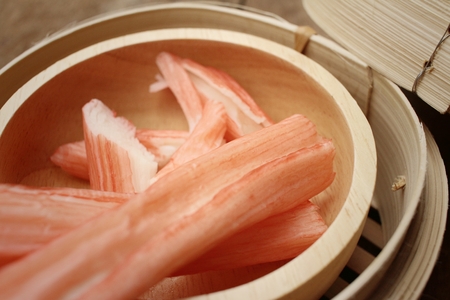 Crab stick in bowl on brown backgroundの写真素材