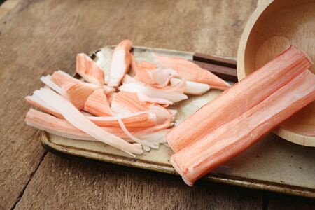 Crab stick in plate on brown backgroundの写真素材