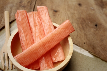 Crab stick in bowl on brown backgroundの写真素材