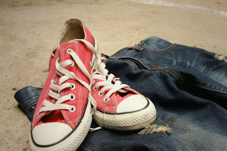 Red shoes with jeans on cement background.の写真素材