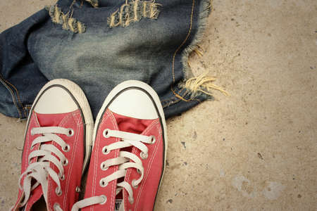 Red shoes with jeans on cement background.の写真素材