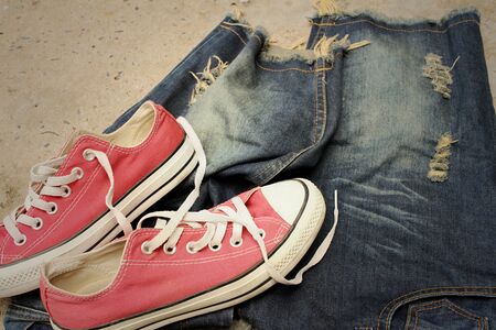 Red shoes with jeans on cement background.