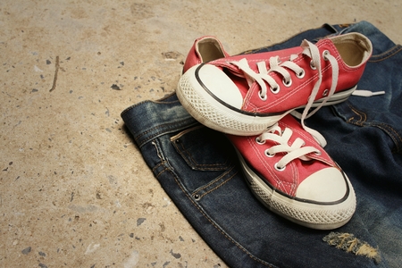 Red shoes with jeans on cement background.の写真素材