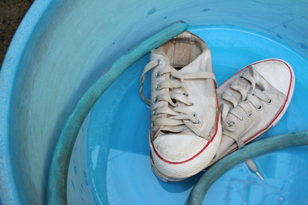 Sneakers wash enameled bowl with soapy water.の写真素材