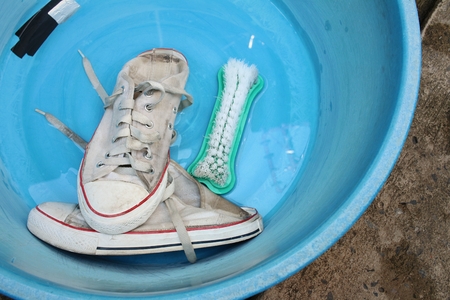 Sneakers wash enameled bowl with soapy water.の写真素材