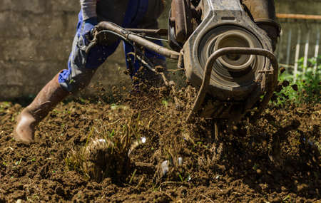 Farmer using machine mart cultivator for ploughing soil