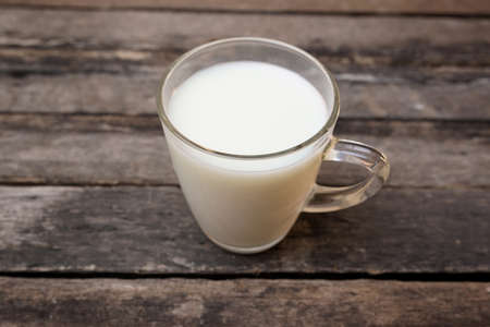 Glass of milk standing on old wooden tableの写真素材