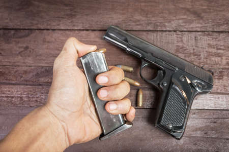 hand with bullet and Semi-automatic 9mm gun on wooden background の写真素材