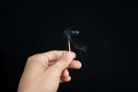 hand holding an extinguished matchstick on black backgroundの写真素材