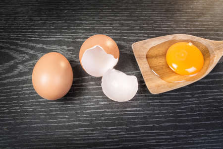 Yolk in wooden spoon on wooden background