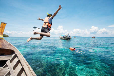 Snorkeling divers jump in the waterの写真素材