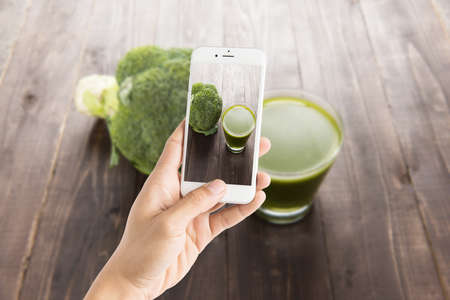 Taking photo of broccoli juice on wood tableの写真素材
