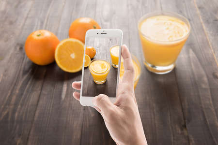 Taking photo of orange juice and orange on the wooden background.の写真素材
