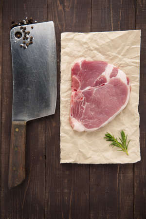 Raw pork chop steak and cleaver on wooden background.の写真素材