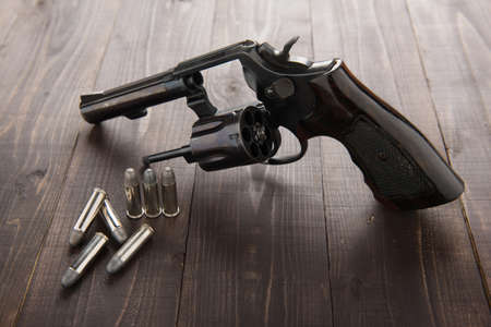 black revolver gun with bullets isolated on wooden background.