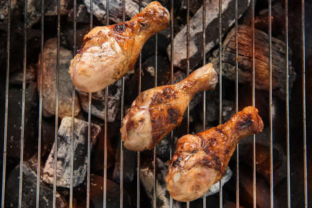 Chicken legs grilling over flames on a barbecueの写真素材