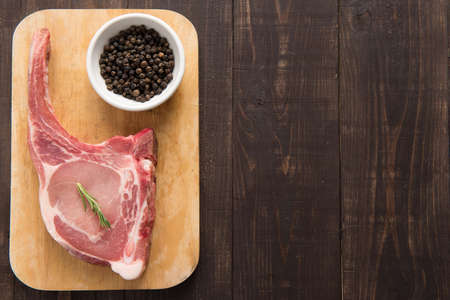 Fresh pork chops and pepper on wooden background.