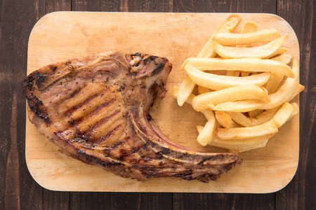 Pork meat grilled and french fries on wooden backgroundの写真素材