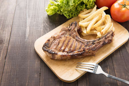 Grilled steak with french fries on a wooden boardの写真素材