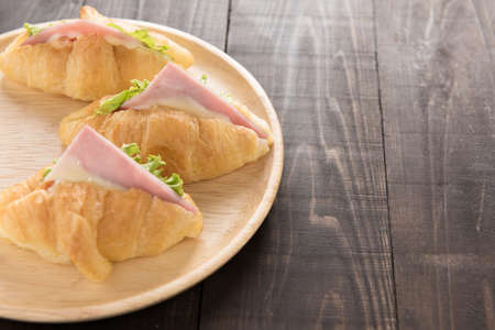 Croissant with parma ham and lettuce on wooden table.の写真素材