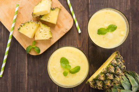 Pineapple smoothie with fresh pineapple on wooden table.の写真素材
