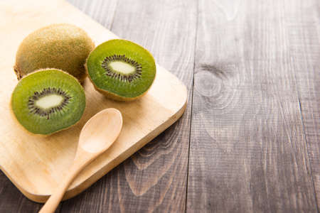 Fresh kiwis fruit and spoon on wooden board.の写真素材