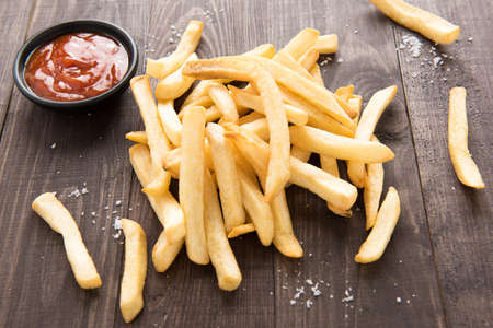French fries with ketchup on wooden background.