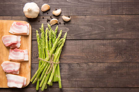 Smoked bacon with fresh asparagus on wooden background.の写真素材