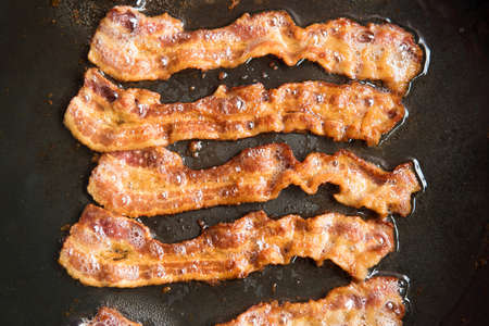 Bacon strips being cooked in frying pan. Close up.の写真素材
