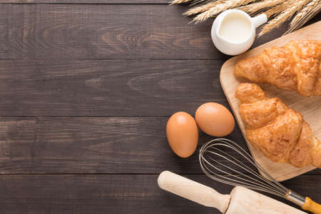 Freshly baked croissants, milk and eggs on wooden background.の写真素材