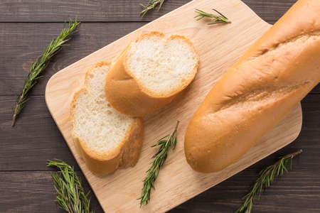 Bread baguette and rosemary on wooden background.の写真素材