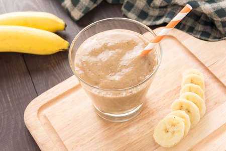 Banana smoothie and fresh banana on wooden background.の写真素材