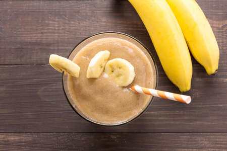 Banana smoothie and fresh banana on wooden background. Top view.の写真素材
