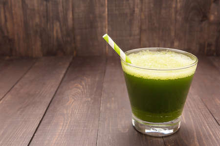 Healthy green smoothie on rustic wood background.