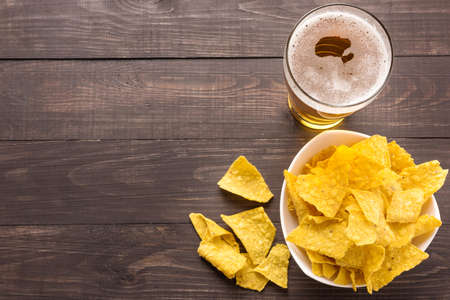 Glass of beer with nachos chips on a wooden background.の写真素材