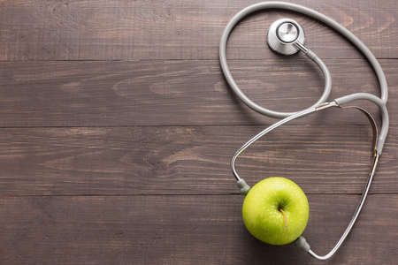 Stethoscope and green apple on wooden background.の写真素材