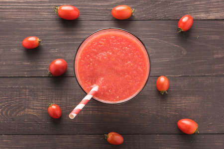 Glass of red tomato juice on wooden table.の写真素材