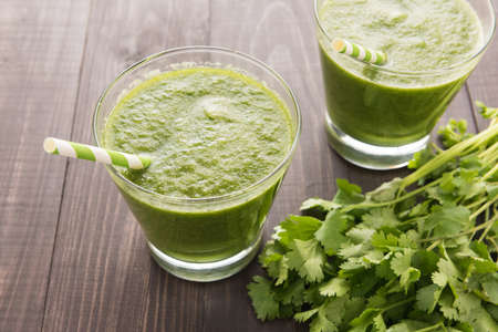 Healthy green vegetables and green fruit smoothie on rustic wood table.