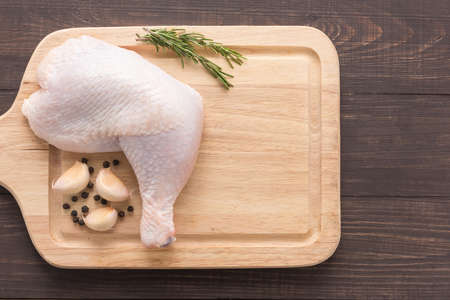 Raw chicken leg on cutting board on wooden background.の写真素材