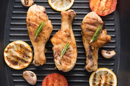 Grilled chicken drumstick and vegetables in a pan.