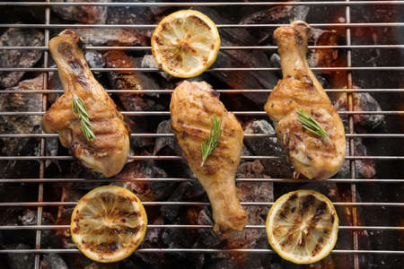 Grilled chicken drumstick over flames on a barbecue.の写真素材