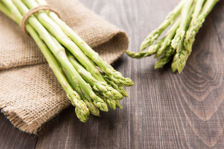 Bunch of fresh green asparagus on a rustic wooden table.の写真素材