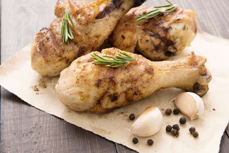 Grilled chicken drumstick and vegetable on wooden background.