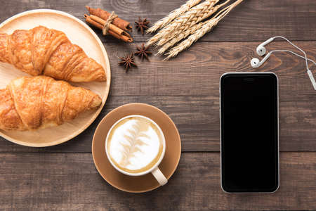 Coffee cup and fresh baked croissants on wooden background. Top View.の写真素材
