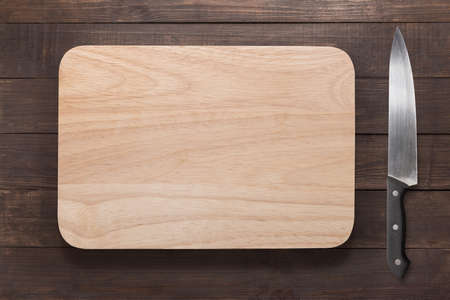 Knife and cutting board on the wooden background.