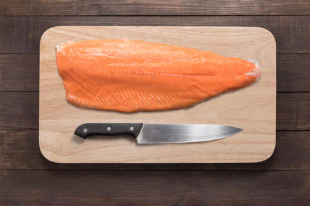 Fresh salmon and knife on cutting board on the wooden table. Top view.の写真素材