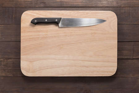 Knife and cutting board on the wooden background.の写真素材