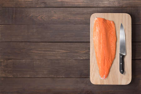 Fresh salmon and knife on cutting board on the wooden table. Top view.の写真素材