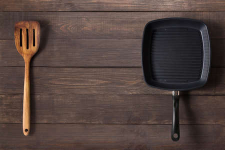 Cast iron frying pan and spatula on the wooden background.の写真素材