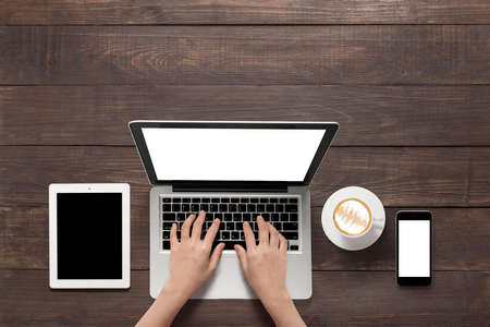 Using laptop, tablet, smartphone and a cup of coffee on wooden background.の写真素材